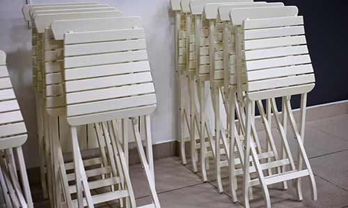 Stacks of white folding chairs leaning on a wall, waiting for a better storage solution