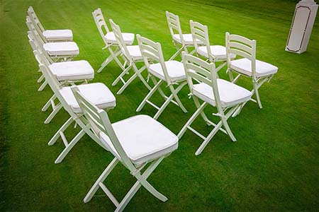 Set of white plastic folding chairs on a green lawn